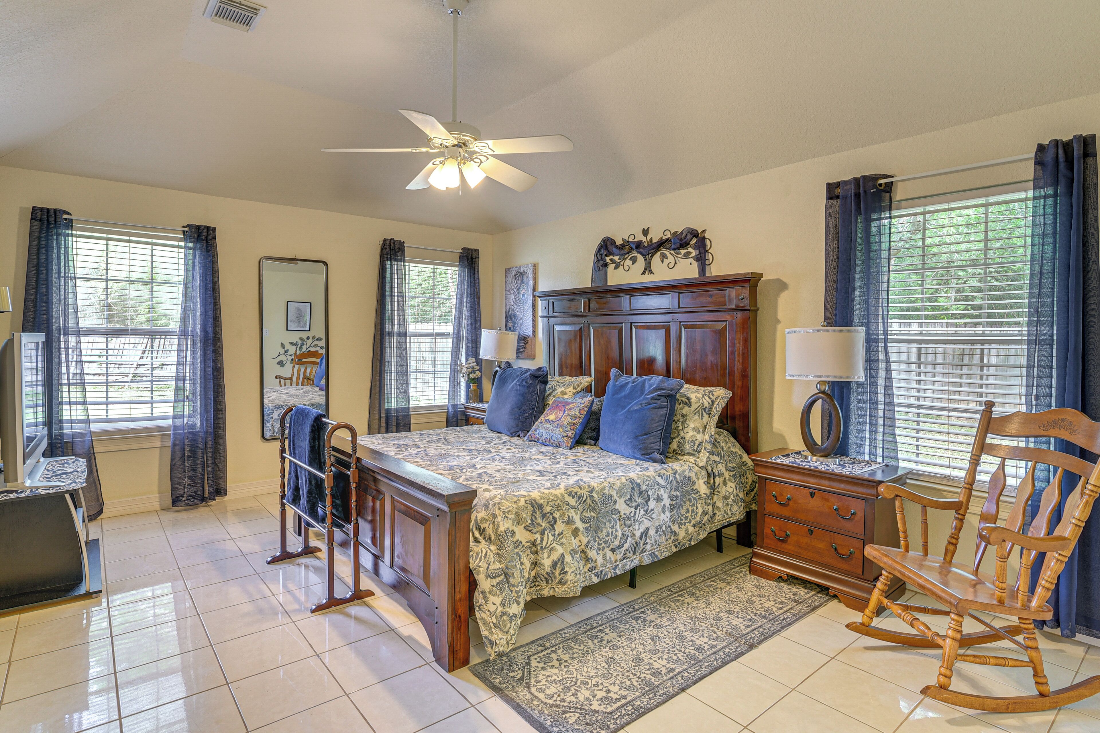 A bedroom with a bed, dresser, chair, and a ceiling fan.