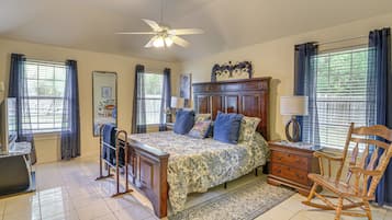 A bedroom with a bed, dresser, chair, and a ceiling fan.