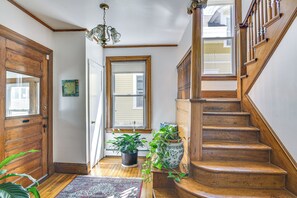Eine Holztretreppe, ein Blumentopf und ein gemustertes Teppich im Flur.