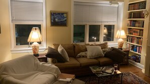 A living room with a sofa, armchair, and a bookshelf. - 3-bedroom townhouse w/AC  Downtown walk to PPG Arena-Cultural Dist/Stadiums (Pittsburgh)
