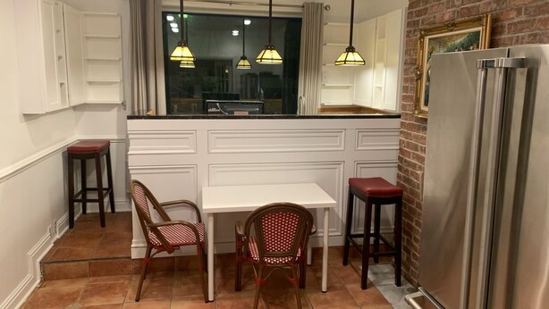 A kitchen with white cabinetry, a dining table, two chairs, a refrigerator, and pendant lights. - 3-bedroom townhouse w/AC  Downtown walk to PPG Arena-Cultural Dist/Stadiums (Pittsburgh)