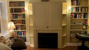 A cozy living room with a fireplace, bookshelves, and a comfortable seating area. - 3-bedroom townhouse w/AC  Downtown walk to PPG Arena-Cultural Dist/Stadiums (Pittsburgh)