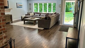 A living room with a sectional sofa, a coffee table, and a fireplace. - Located directly on Pond, Swimming, Kayaking, Fishing, Beach Pass, A/C, Clean! (Barnstable)