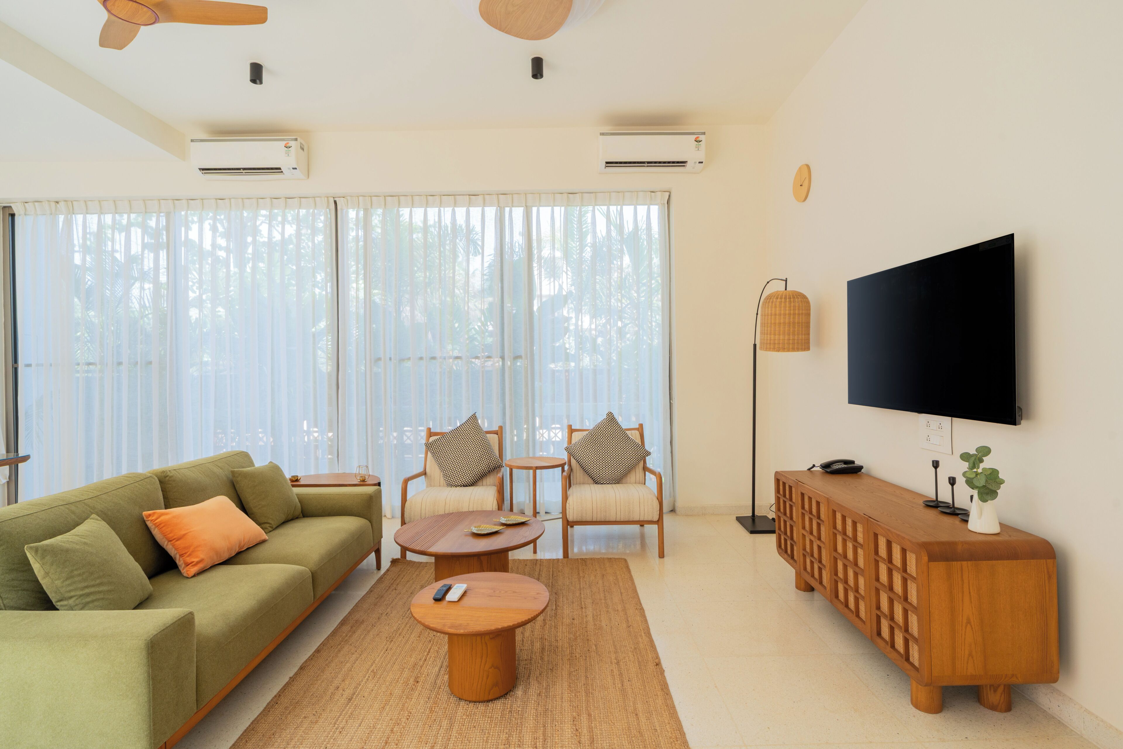 A modern living room with a sofa, two armchairs, a coffee table, a TV, and a wooden console.