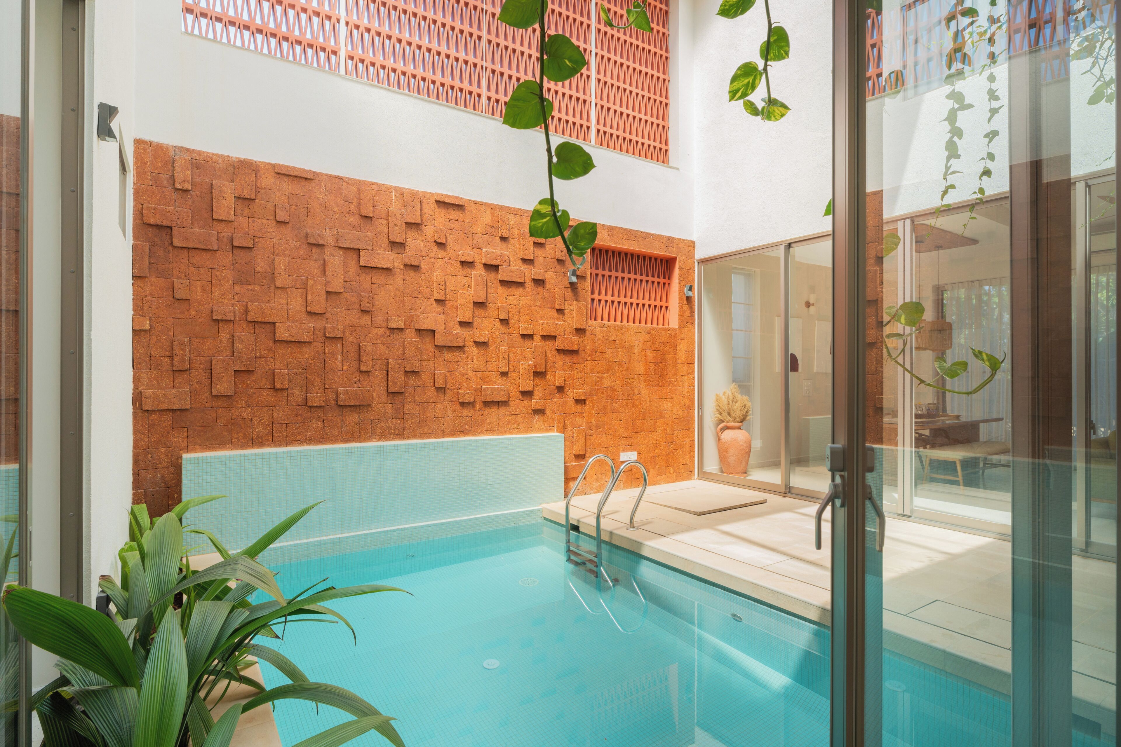 A swimming pool with a brick wall and glass doors.