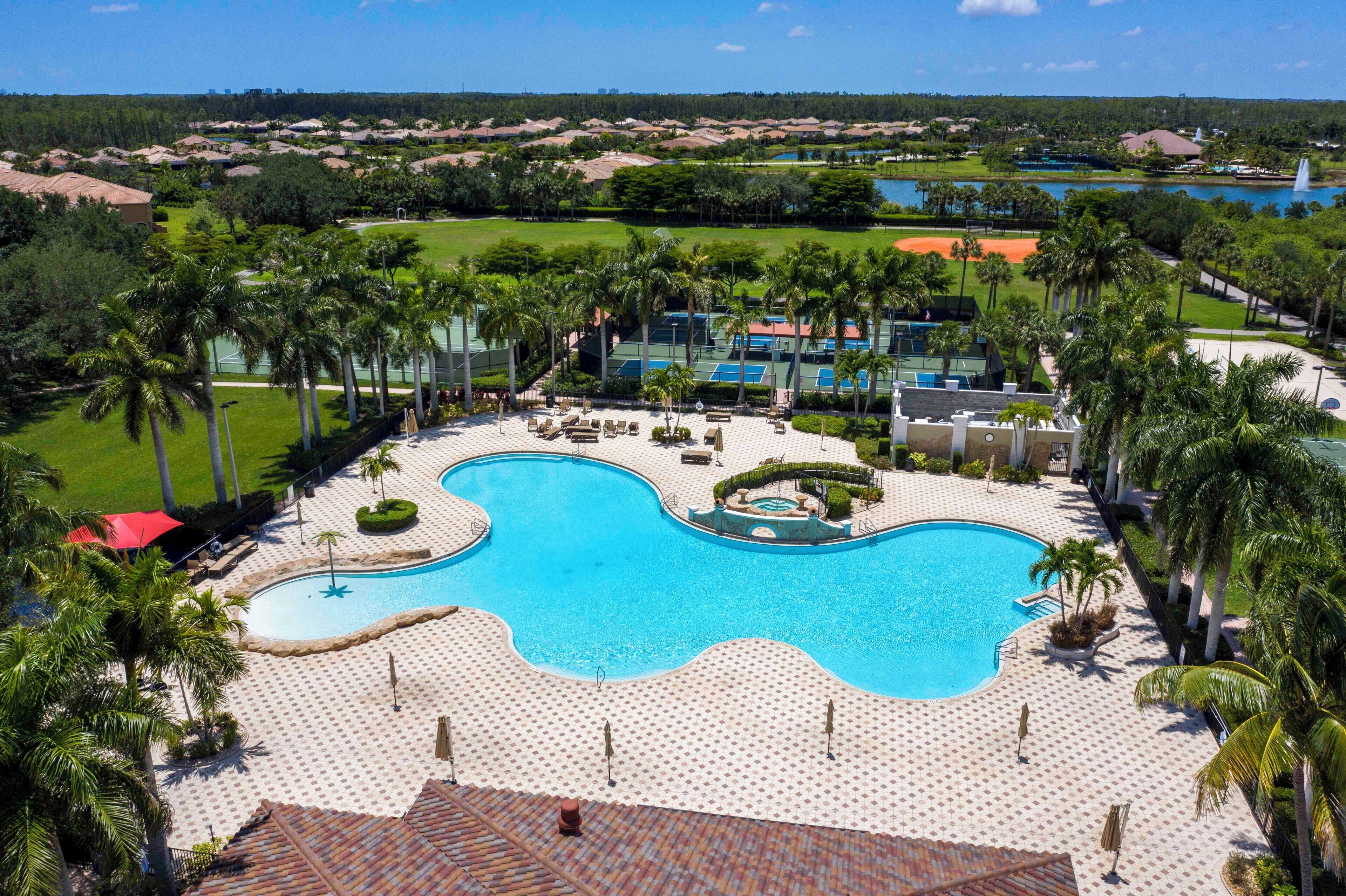 A resort with a large swimming pool, palm trees, and a golf course in the background.