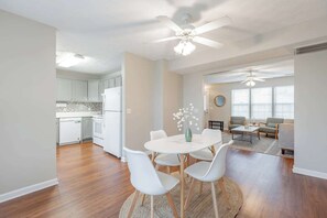 A modern kitchen with white cabinets, a white refrigerator, and a dining area with a round table and white chairs. - Newly renovated home, across the street from a vibrant, peaceful state nature park! (Chattanooga)