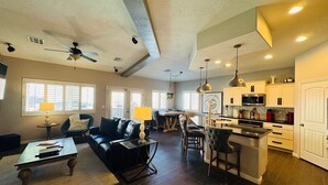 A spacious living room with a black leather sofa, a coffee table, and a dining area with a chandelier. - Sunstone Escape | Pool + Hot Tub | 3BR | 9 Min to Sports Complex | $510 Free Activities (Mesquite)