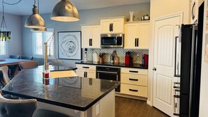 A modern kitchen with white cabinets, a black refrigerator, stainless steel appliances, and pendant lighting. - Sunstone Escape | Pool + Hot Tub | 3BR | 9 Min to Sports Complex | $510 Free Activities (Mesquite)
