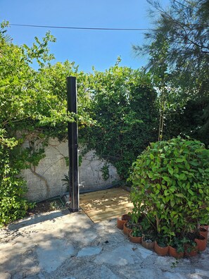 A concrete pathway leading to a gate, surrounded by dense greenery and a stone wall. - Unique 3-bedroom apartment with AC and beautiful sea views in charming Baosici (Baosici)