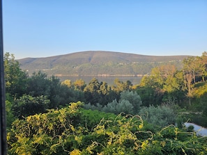 Ein See, umgeben von Hügeln und dichtem Grün.