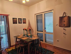 A dining area with a table, chairs, and a decorative wall piece. - Unique 3-bedroom apartment with AC and beautiful sea views in charming Baosici (Baosici)