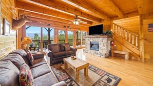 Ein Holzhaus-Interieur mit Kamin aus Stein, einer Couch, einem Couchtisch und einem Fernseher.