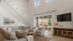 A spacious living area with a sofa, armchairs, a coffee table, and a TV. - Sol Retreat: Steps from Desert Color Lagoon! (St. George)
