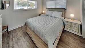 Un dormitorio con cama, mesitas de noche, ventilador de techo y una ventana con persianas.