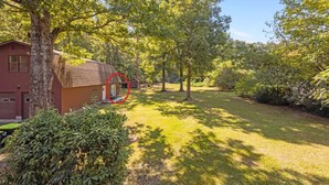 A residential property with a red building, a well-maintained lawn, and mature trees. - Private New Bern Apartment in Quiet Neighborhood (New Bern)