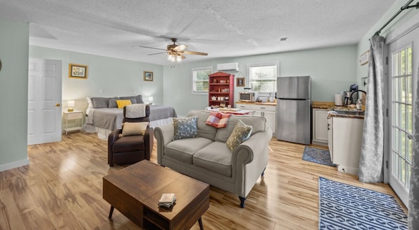 A living room with a sofa, armchair, coffee table, and a ceiling fan.