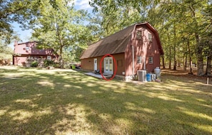 A red barn with a door circled, surrounded by a grassy yard and trees.