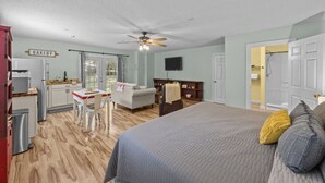 A bedroom with a bed, a desk, a chair, a sofa, a television, and a bathroom with a shower. - Private New Bern Apartment in Quiet Neighborhood (New Bern)