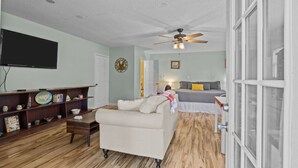 A living room with a sofa, a television, a bookshelf, and a ceiling fan. - Private New Bern Apartment in Quiet Neighborhood (New Bern)