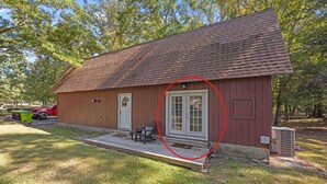 A single-story building with a red exterior, a front porch, and a door with glass panels. - Private New Bern Apartment in Quiet Neighborhood (New Bern)