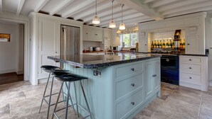 A spacious kitchen with a large island, bar stools, and a wine fridge. - Drift Cottage, Salthouse, Norfolk (Salthouse)