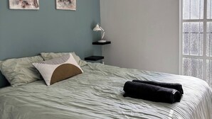 A bedroom with a bed, two wall-mounted paintings, a bedside table with a lamp, and a window with a view. - Bheka Guest House Parktown North, Johannesburg (Johannesburg)