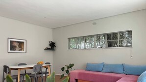 A modern living room with a sofa, a dining table with chairs, a window with blinds, and a framed picture on the wall. - Bheka Guest House Parktown North, Johannesburg (Johannesburg)