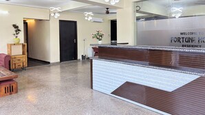Un espace d’accueil comprenant un comptoir de réception, des ventilateurs de plafond et un panneau d’accueil.