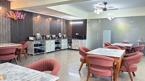 Un restaurant doté de tables surmontées de plateaux en marbre et de chaises rembourrées, d’un espace buffet avec différents stands de nourriture et d’un design moderne au niveau du plafond.