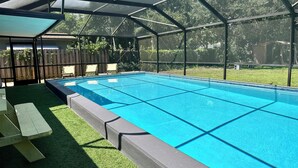 Une piscine couverte avec vue sur une cour arrière clôturée et une clôture en bois en arrière-plan.