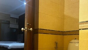 Een badkamer met toilet en douche, met een bed in de aangrenzende kamer.
