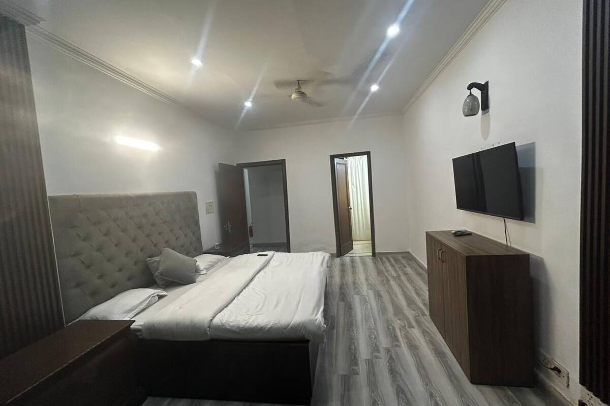 Un dormitorio con cama, armario, televisor y ventilador de techo.