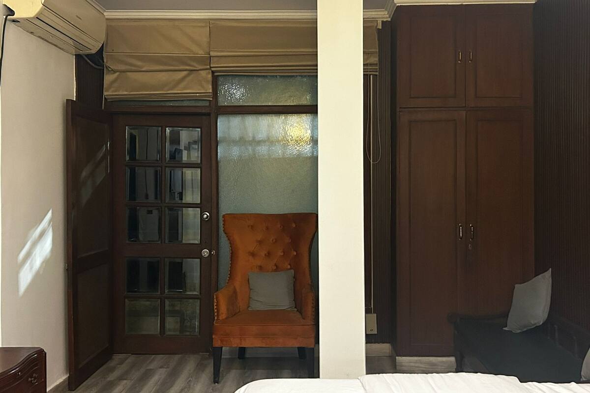 Habitación de hotel con cama, armario de madera, puerta de cristal y una silla.