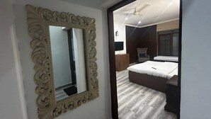 Een slaapkamer met een grote spiegel, een bed, een dressoir en een televisie.