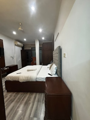 A bedroom with a bed, bedside tables, a wardrobe, and an air conditioning unit. - The Hideout GK (New Delhi)