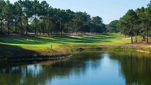 A golf course with a pond, trees, and a flagstick. - Villa in Quinta do Perú Golf & Country Club (Quinta do Conde)