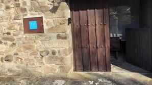 A stone building with a wooden door and a signboard. - THE SHELTER OF MOLINOS DE RAZÓN (Molinos de Razón)