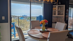 Un espace repas avec vue sur l’océan, un balcon doté d’une balustrade et une table avec des chaises.