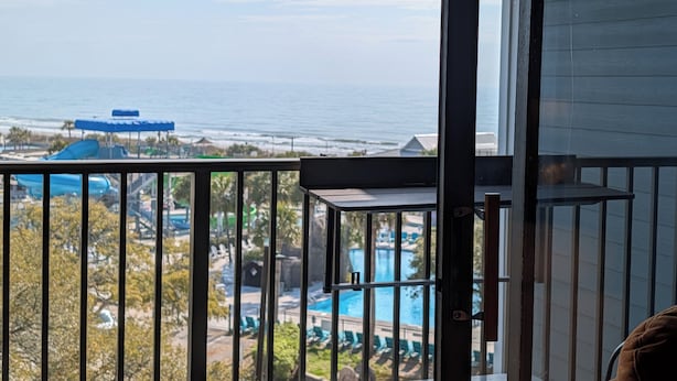Un balcon avec vue sur l’océan, une piscine et un toboggan aquatique.