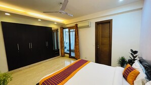Ein Schlafzimmer mit einem Bett, einem Deckenventilator, einem Kleiderschrank und einer Tür, die auf einen Balkon führt.