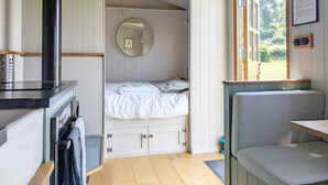 Een slaapkamer met een bed, een spiegel, een raam en een houten plafond.