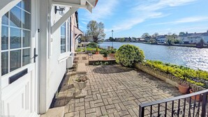 A balcony with a view of a river, a stone pathway, and a small garden area. - Thimble Cottage - Emsworth  -  a family house that sleeps 2 guests  in 1 bedroom (Emsworth)
