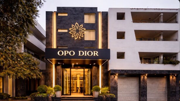 En modern byggnad med en framträdande skylt med texten ”OPO DIOR”, stora fönster och en väl upplyst entré.
