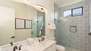 Ein Badezimmer mit großem Spiegel, zwei Waschbecken, Toilette und Dusche.