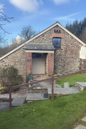 Un edificio de piedra con una escalera de madera y una puerta.