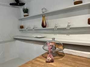 Una cocina con paredes blancas, estantes de madera y encimera de madera.