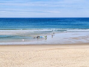 Ein Strand mit Menschen, die spazieren gehen und Surfbretter tragen.