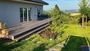 Una casa moderna con terraza, ventanas amplias y vistas al campo.