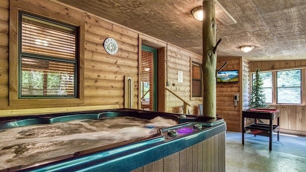 Eine Holzhütte mit Whirlpool, Holzvertäfelung an Wänden und Decke sowie einem Fernseher.